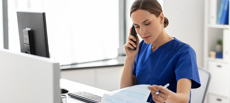 Assistante médicale au téléphone consulte un dossier - La Prévention Médicale