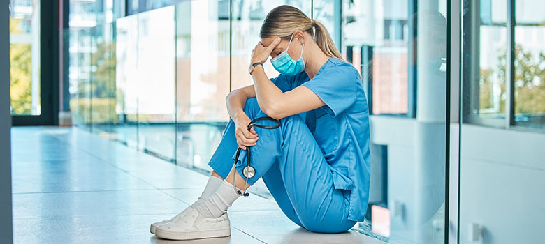 Une femme soignante déprimée est assise au sol | La Prévention Médicale
