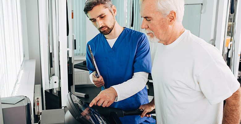Un kinésithérapeute programme le tapis de marche avec son patient - La Prévention Médicale