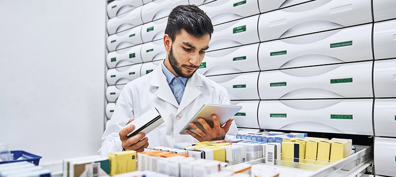Un pharmacien prend des médicaments dans le tiroir en examinant l'ordonnance - La Prévention Médicale