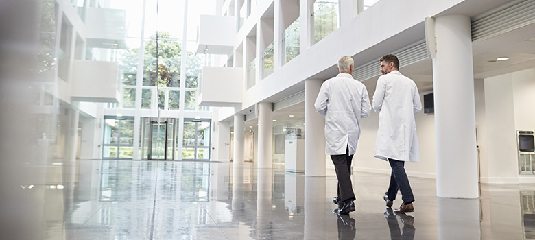 Deux médecins traversent un couloir d'hôpital - La Prévention Médicale