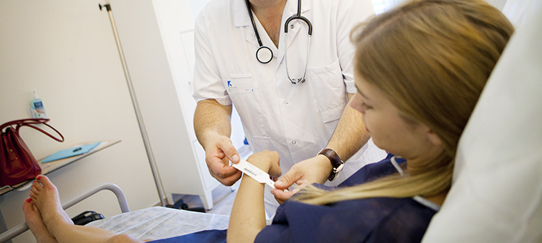 Un infirmier pose un bracelet d'identité à une patiente - La Prévention Médicale Un infirmier pose un bracelet d'identité à une patiente - La Prévention Médicale