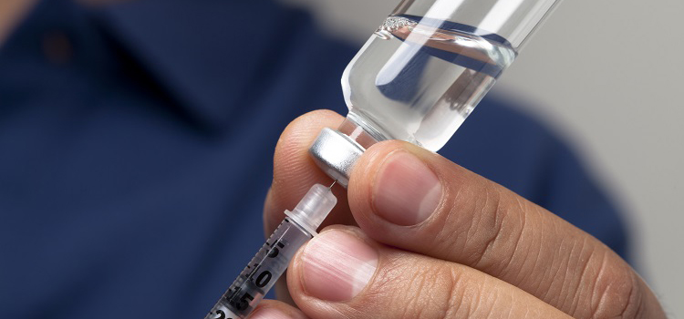 Une main prépare une seringue en prélevant une dose de médicament depuis un flacon - La Prévention Médicale