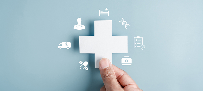 Main tenant une croix blanche symbolisant les solutions de santé - La Prévention Médicale Main tenant une croix blanche symbolisant les solutions de santé - La Prévention Médicale