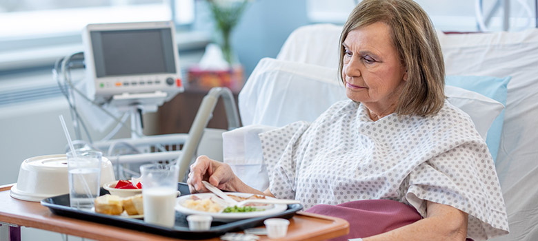Une dame âgée prenant son repas dans le lit de l'hôpital - PM