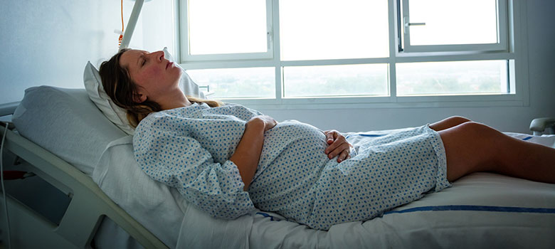 Femme enceinte souffrante allongée sur le lit à l'hôpital - La Prévention Médicale