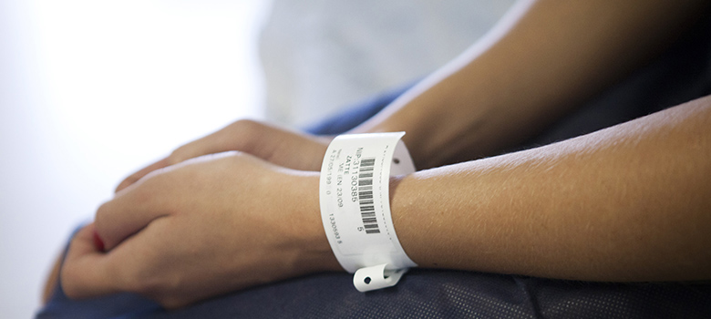 Une patiente assise portant un bracelet de l'hôpital  - La Prévention Médicale