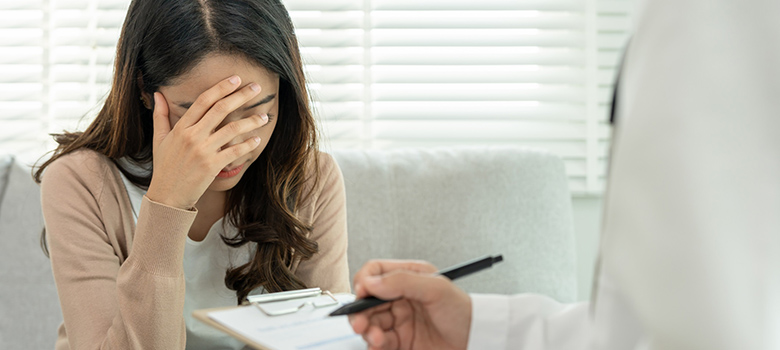 Une femme épuisée assise face au médecin qui prend des notes - La Prévention Médicale