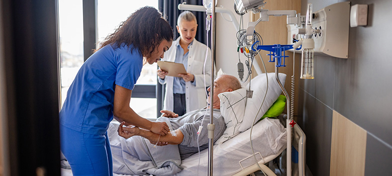 Une infirmière pose une perfusion à un homme âgée à l'hôpital - La Prévention Médicale