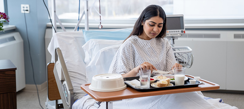 Une femme hospitalisée prend son repas - La Prévention Médicale