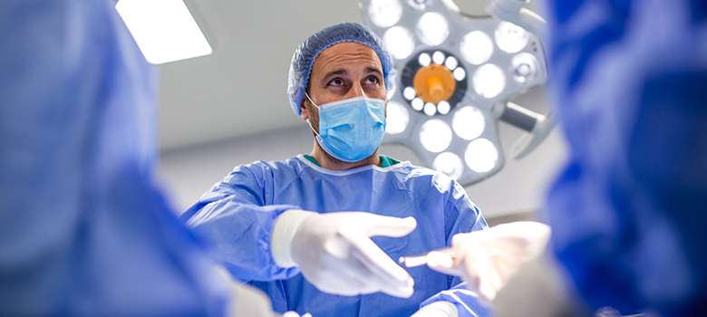 Gros plan sur un chirurgien au bloc qui saisit l'instrument qui lui est tendu - La Prévention Médicale Gros plan sur un chirurgien au bloc qui saisit l'instrument qui lui est tendu - La Prévention Médicale