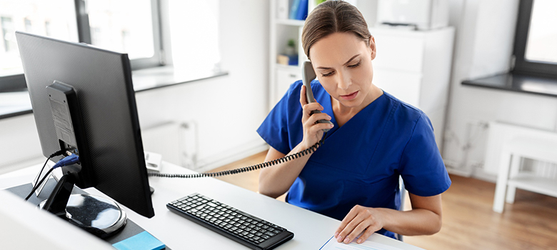 Une secrétaire médicale au téléphone consulte un document - La Prévention Médicale Une secrétaire médicale au téléphone consulte un document - La Prévention Médicale