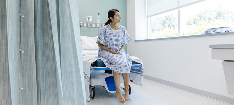 Une patiente regarde par la fenêtre en attendant une consultation à l'hôpital - La Prévention Médicale Une patiente regarde par la fenêtre en attendant une consultation à l'hôpital - La Prévention Médicale
