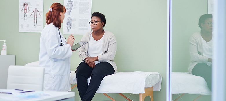 Une femme médecin apporte des explications à sa patiente assise sur la table d'examen - La Prévention Médicale Une femme médecin apporte des explications à sa patiente assise sur la table d'examen - La Prévention Médicale