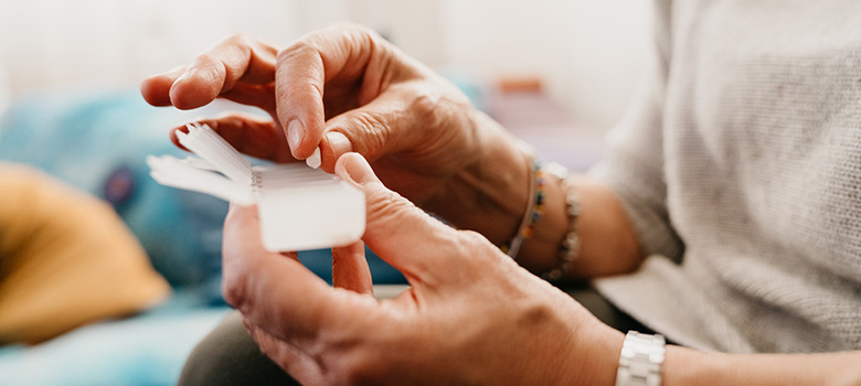 Une femme prend un médicament dans un pilulier - La Prévention Médicale