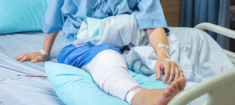 Une patiente alitée avec des bandages à la jambe - La Prévention Médicale