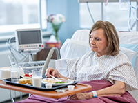 Une dame âgée prenant son repas dans le lit de l'hôpital - PM