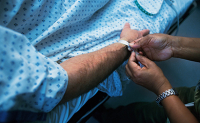 Un professionnel de santé pose un bracelet d'identitovigilance sur un patient - La Prévention Médicale