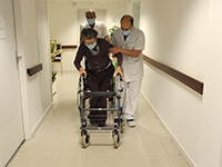 Des aides-soignants accompagnent une femme âgée qui se déplace en déambulateur - MACSF