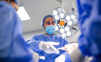 Gros plan sur un chirurgien au bloc qui saisit l'instrument qui lui est tendu - La Prévention Médicale Gros plan sur un chirurgien au bloc qui saisit l'instrument qui lui est tendu - La Prévention Médicale