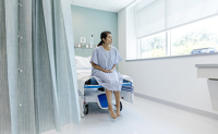 Une patiente regarde par la fenêtre en attendant une consultation à l'hôpital - La Prévention Médicale Une patiente regarde par la fenêtre en attendant une consultation à l'hôpital - La Prévention Médicale