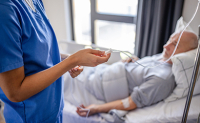 Une infirmière vérifie la perfusion d'un patient âgé alité - La Prévention Médicale Une infirmière vérifie la perfusion d'un patient âgé alité - La Prévention Médicale
