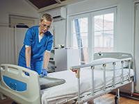 Une aide-soignante fait le lit dans une chambre d'hôpital - La Prévention Médicale