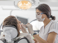 Une femme dentiste pratique des soins sur une patiente - La Prévention Médicale