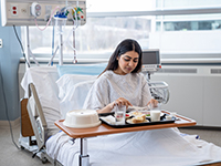 Une femme hospitalisée prend son repas - La Prévention Médicale