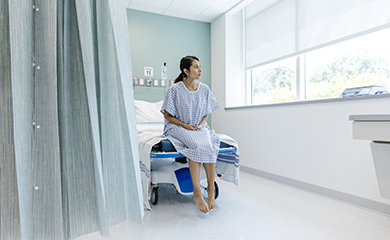 Une patiente regarde par la fenêtre en attendant une consultation à l'hôpital - La Prévention Médicale