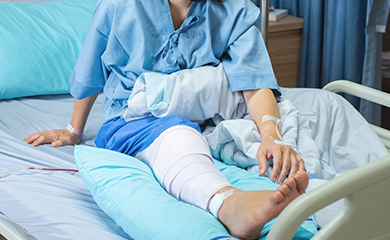 Une patiente alitée avec des bandages à la jambe - La Prévention Médicale